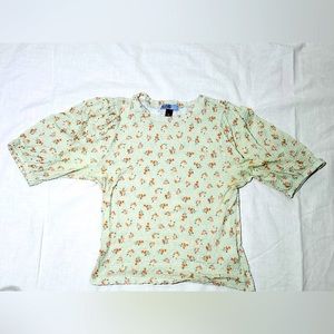 Mint green top with slight puffed sleeves, floral decor and thin material.